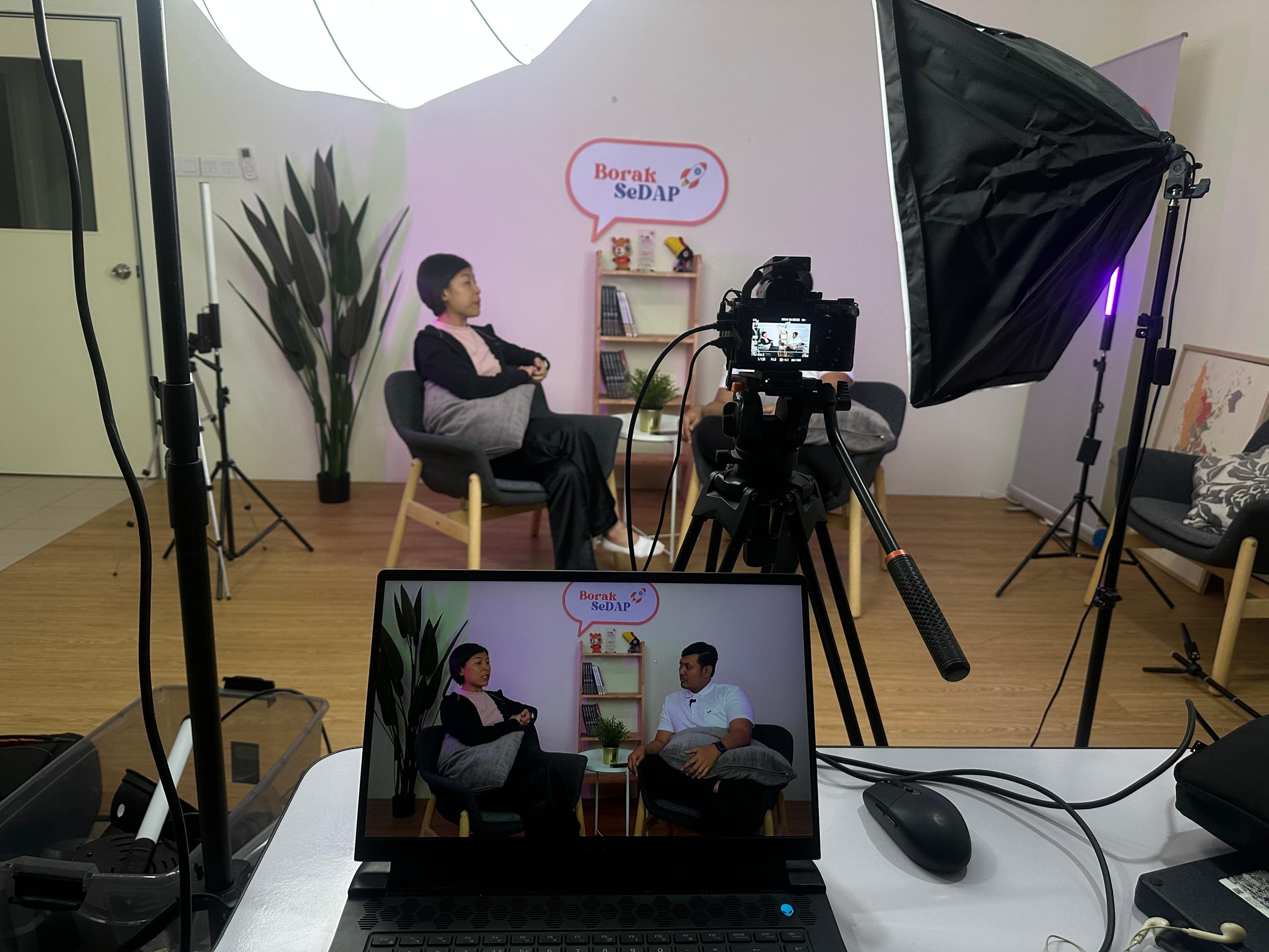 Behind the scenes podcast recording setup with camera, monitor, and lighting